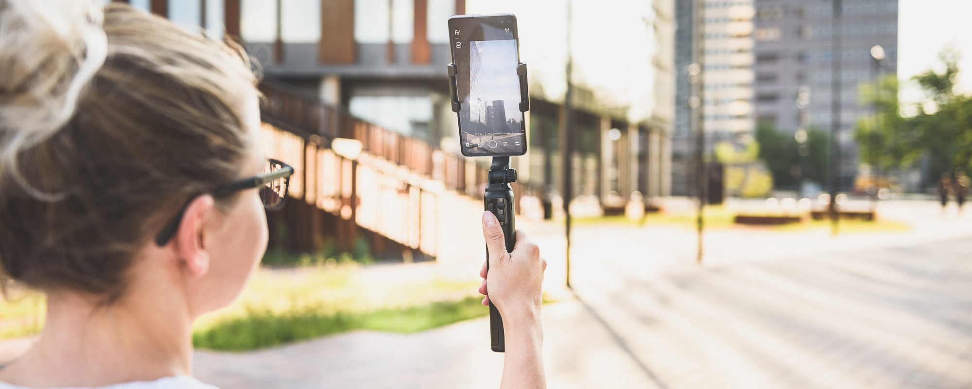 Dziewczyna nagrywa smartfonem umieszczonym na gimbalu widoki pokazujace urok miasta